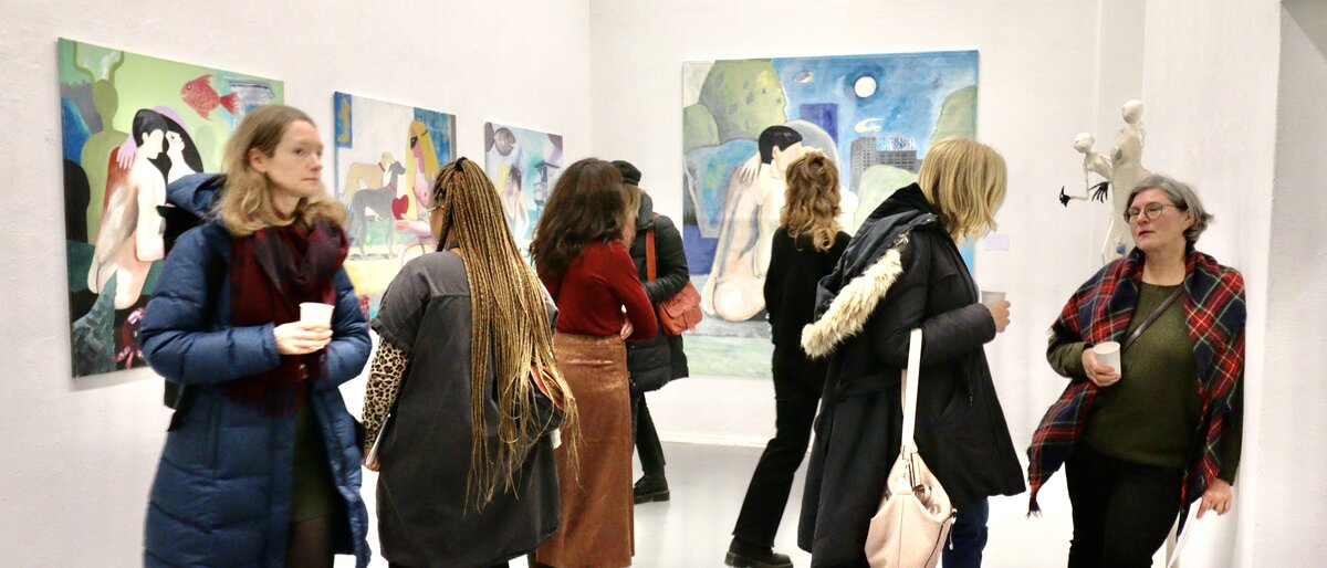 Besucher einer Vernissage schauen sich die Kunstwerke an.