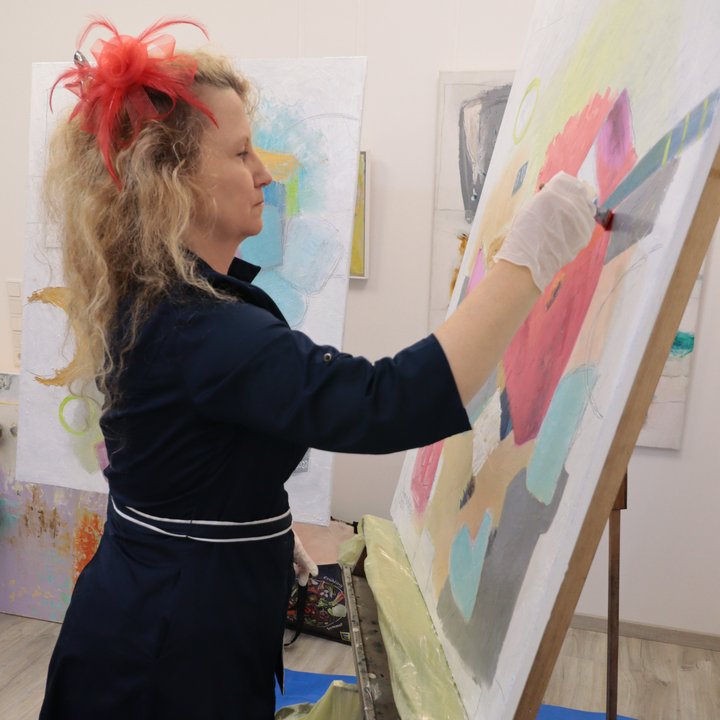 Diana Achtzig steht an ihrer Staffelei und mal zeitgenössische Wandbilder