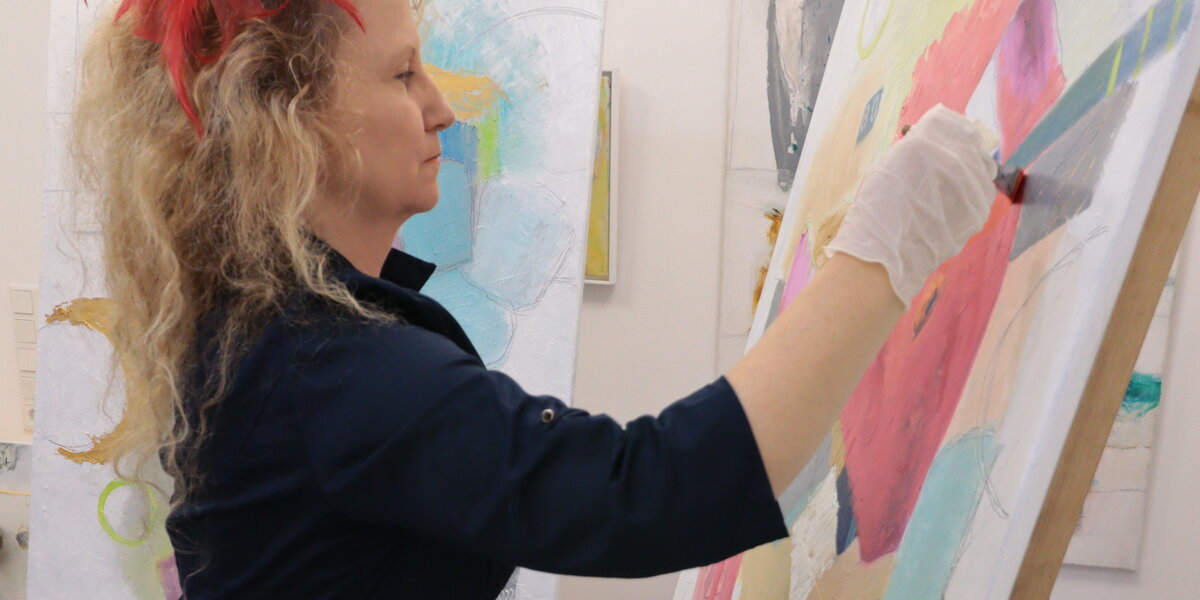 Diana Achtzig steht an ihrer Staffelei und mal zeitgenössische Wandbilder