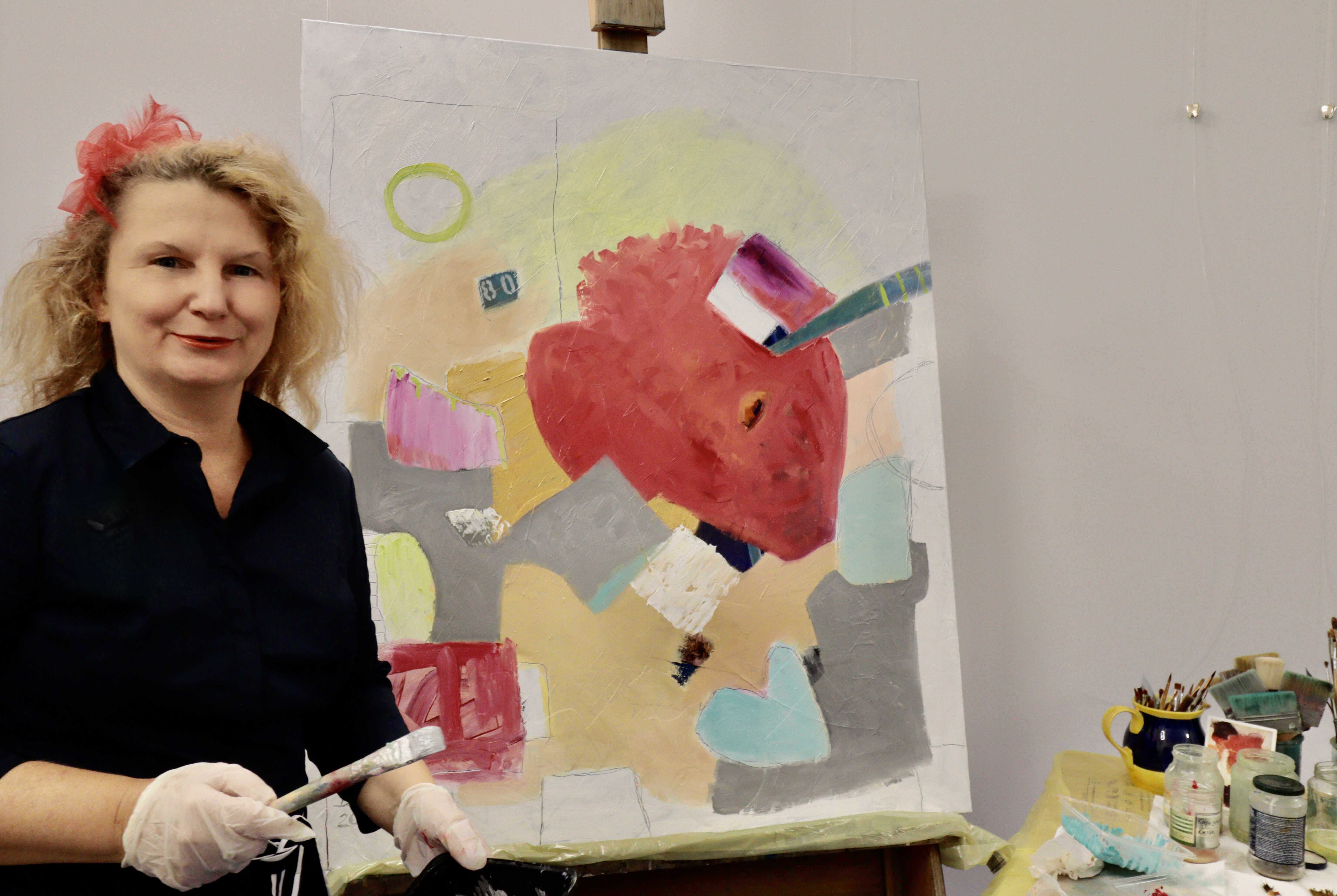 Die Gegenwartsmalerin Diana Achtzig steht vor ihrem abstrakten Ölbild auf Leinwand