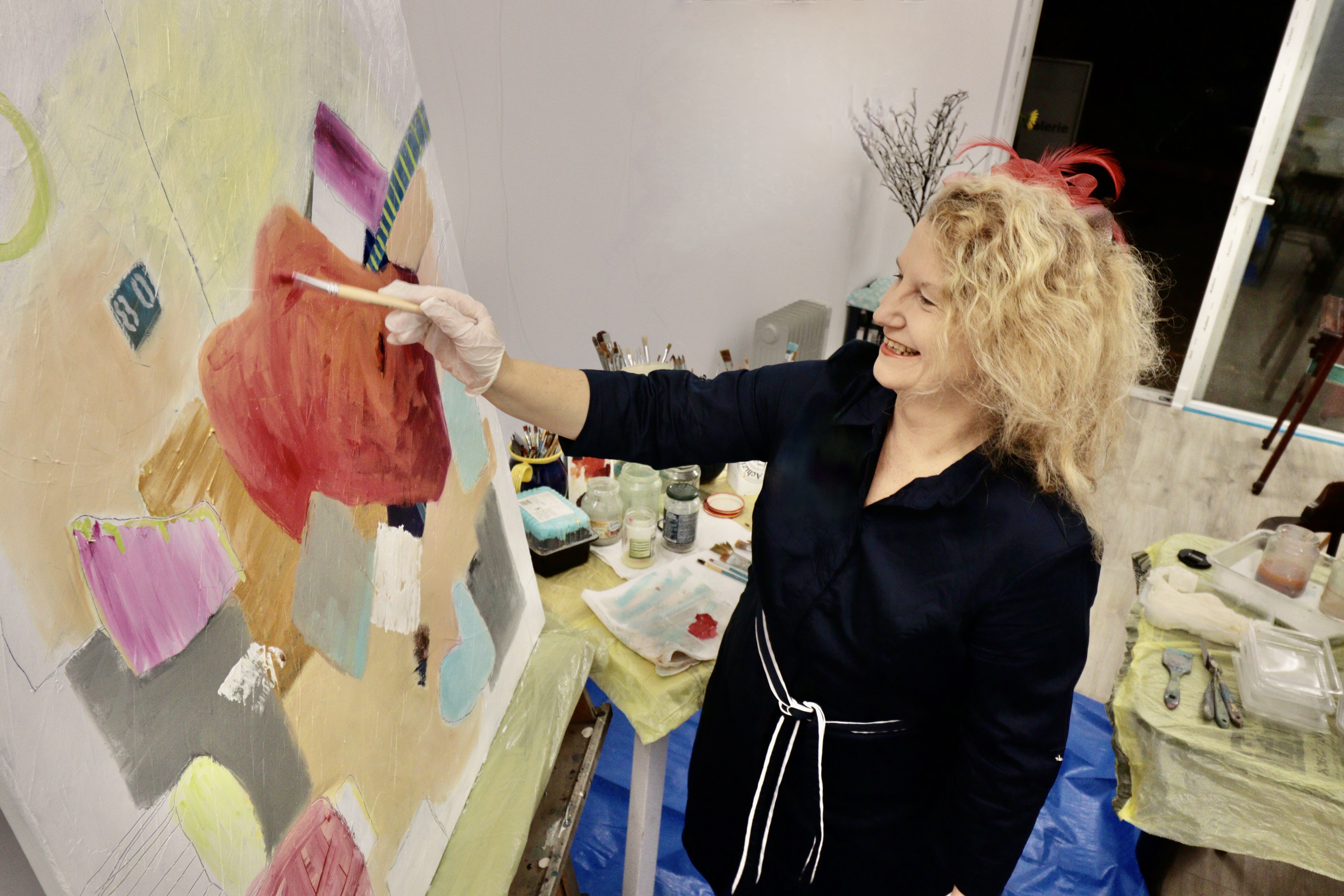 Die Künstlerin Diana Achtzig steht an ihrer Staffelei und malt abstrakte Bilder